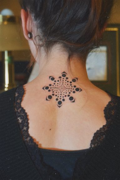 Tatouage délicat en forme de flocon de neige sur le dos d'une femme.