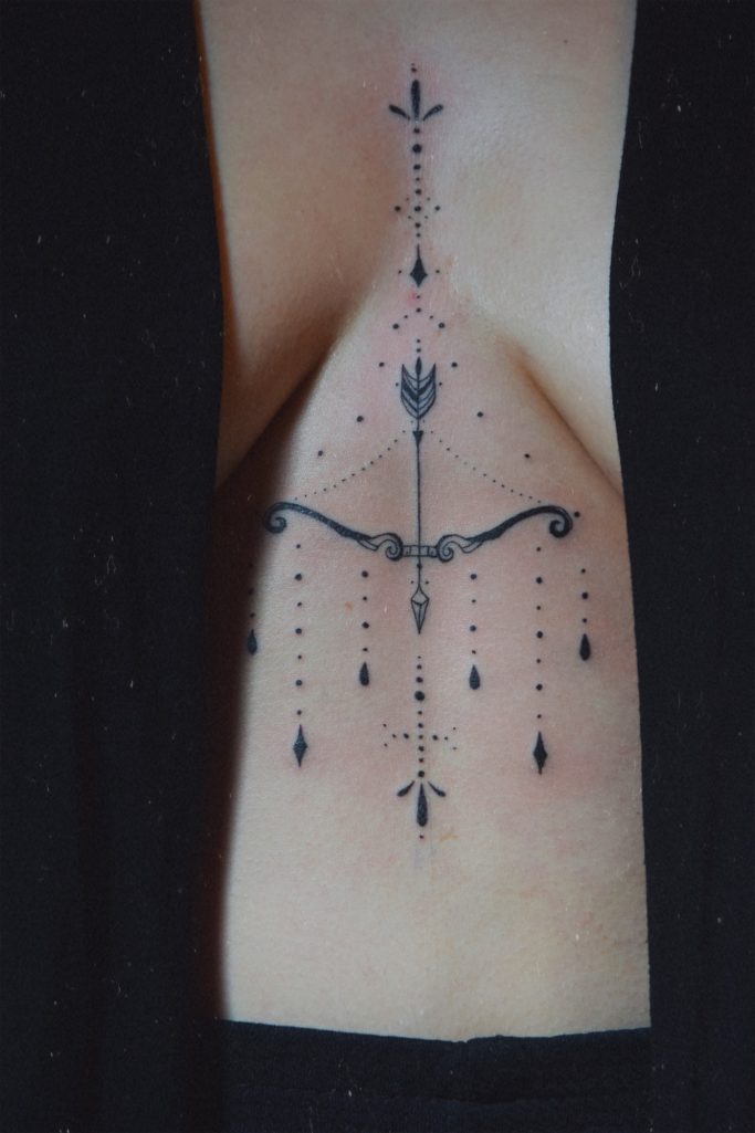 Tatouage noir complexe sur le torse avec motifs et lignes géométriques.