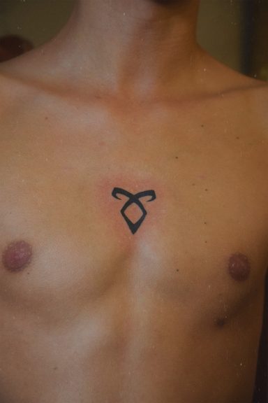 Tatouage noir de rune sur le torse d'un homme.