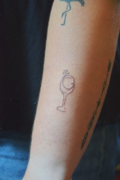 Un tatouage représentant un verre à vin avec un motif stylisé.