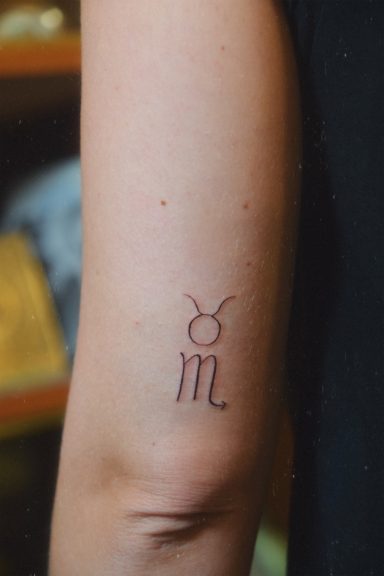 Tatouage représentant le symbole du Taureau et du Scorpion sur un bras.