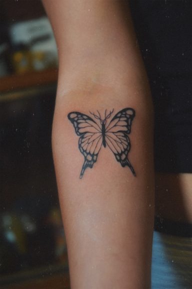 Tatouage d'un papillon noir sur le bras.