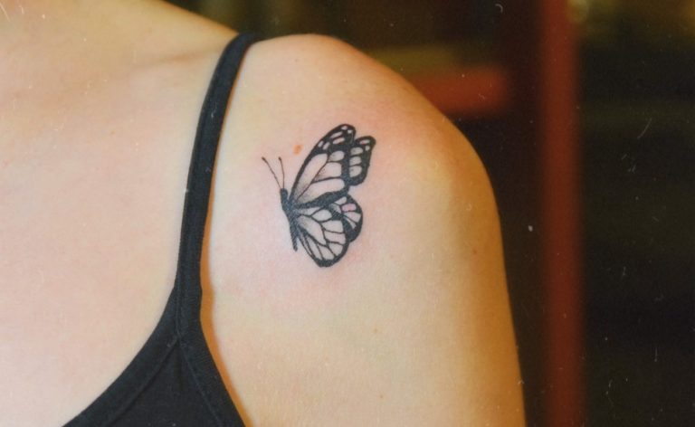 Tatouage d'un papillon sur l'épaule d'une personne.