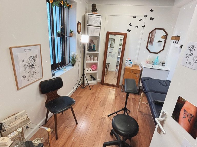 Intérieur d'un espace de travail de tatouage avec des chaises, un miroir et des décorations murales. Dans un style floral vintage.