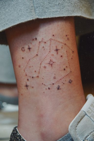 Tatouage de constellations entouré d'étoiles sur la cheville.