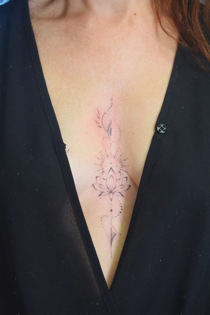 Tatouage délicat sur la poitrine, représentant des motifs floraux et géométriques.